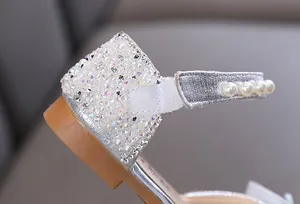 Detailopname van zilveren prinsessenschoenen voor meisjes met glanzende steentjes en parels