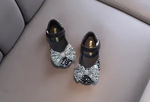 Detailed top view of black girl's princess shoes with sparkling sequined bows and rhinestones.