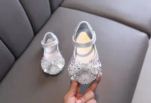 Close-up of silver sequined princess shoes for girls with a large sparkling bow
