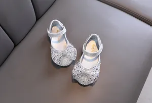 Macro view of silver glitter Mary Jane shoes for girls featuring a large sparkling bow detail