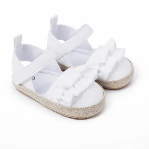 Detalle de zapatos blancos para bebé con diseño de volantes y suela tejida