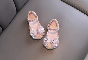 Close-up view of pink girl's Mary Jane shoes decorated with large sparkling sequined bows