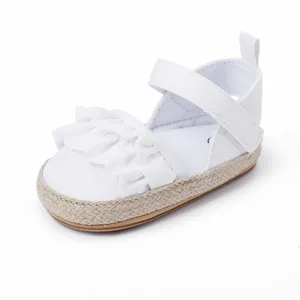 Vista detallada de zapatos blancos para bebés con volantes y suela de yute trenzada.