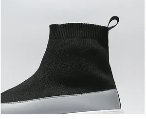 Close-up detail of breathable black knitted high-top sock shoe with grey panel and white sole.