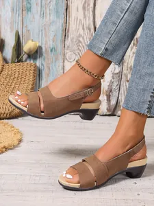 Close-up of brown peep-toe sandals with kitten heel and buckled backstrap on model