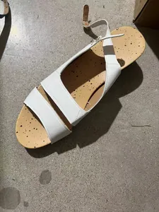 Detailed view of a white platform sandal featuring a speckled tan insole on a grey floor