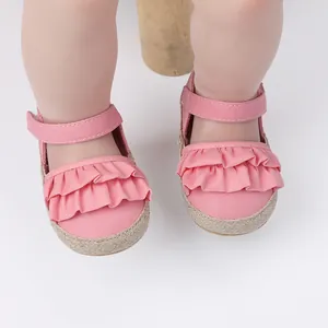 Primer plano de zapatos para caminar de bebé rosa con volantes y suelas trenzadas