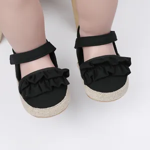 Detalle de zapatos negros para primeros pasos de bebé con volantes y cierre de velcro ajustable