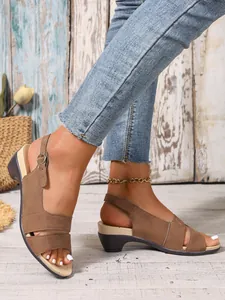 Detail view of brown women's peep-toe wedge sandals with adjustable ankle strap buckle.