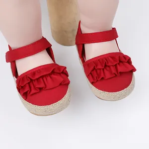 Primer plano de zapatos de bebé rojos con volantes y suelas de yute para primeros pasos