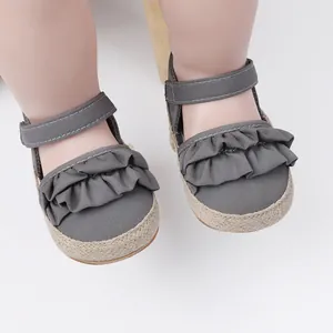 Vista detallada de zapatos de bebé grises con volantes y correas de cierre ajustable