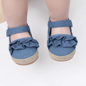 Primer plano de zapatos de bebé en denim azul con volantes y suela de esparto fina