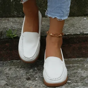 Gros plan détaillé de mocassins blancs décontractés pour femmes portés avec une chevillère d'or.