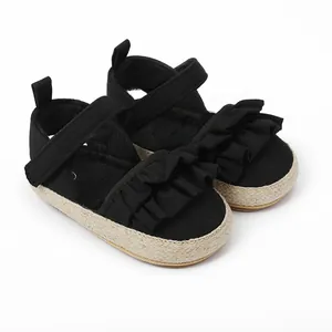Primer plano de sandalias negras para bebé con volantes y suelas de yute trenzado