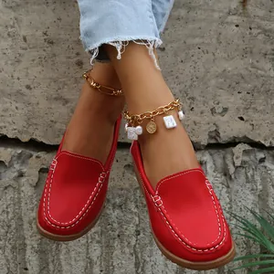 Vue détaillée des mocassins plats rouges pour femmes avec coutures blanches décoratives.