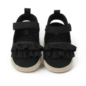 Primer plano de zapatos de bebé negros con volantes y detalle de cierre de velcro