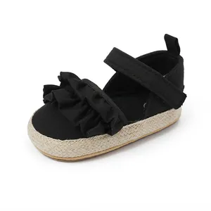 Primer plano de zapato de bebé negro con volantes y suela de esparto trenzada cómoda