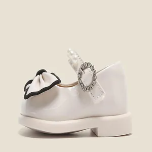 Close-up of girls cream patent leather princess shoes with pearl and bow details.