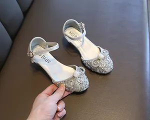 Detailed view of silver glittery girls' dance shoes with rhinestone bows and MG BABY brand