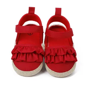 Detalle de zapatos de bebé rojos para caminar con lona con volantes y suela tejida roja
