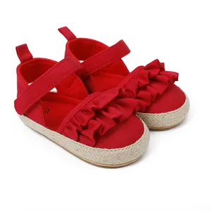Primer plano de zapatos rojos para bebé con volantes y suelas de esparto trenzado.