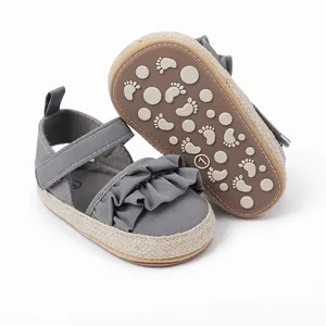 Primer plano de sandalias grises para bebé con diseño de volantes y suelas de goma