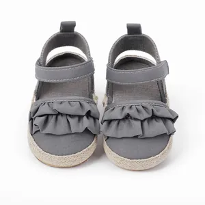Primer plano de zapatos grises para bebé con volantes y suela de esparto trenzada