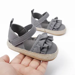 Detalle de zapatos de bebé grises con decoración de volantes y suela de estilo trenzado