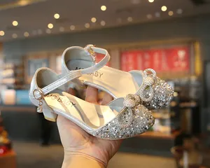 Detailed view of silver sparkly girl's dance shoes with a crystal-encrusted bow detail.