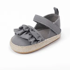 Vista lateral de zapato gris para bebé con tira de volantes y suela de esparto