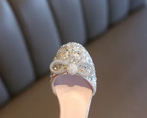 Close-up macro view of the sparkling crystal bow detail on girl's silver rhinestone dance shoes.