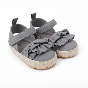 Detalle de zapatos grises para bebé con volantes y suela estilo esparteña