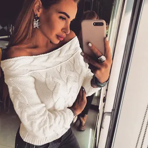 Detail view of a white off-the-shoulder cable-knit sweater worn by a model in a mirror.