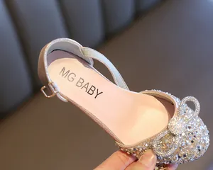 Close-up detail of sparkling rhinestone bow on girl's champagne glitter dress dance shoe