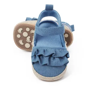 Vista detallada de sandalias de bebé en denim azul claro con volantes y suela antideslizante
