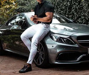 Detail view of men's muscle fit short sleeve polo shirt in black styled with white pants.