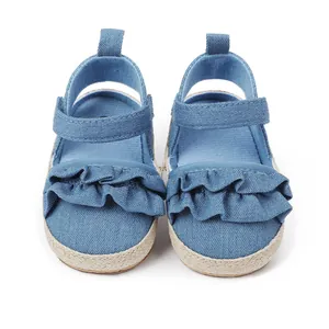 Vista detallada de zapatos azules para bebé con volantes y suela de paja trenzada