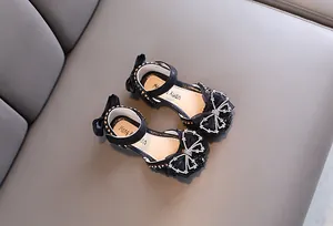 Primo piano di scarpe da principessa nere per bambina con fiocco di strass.