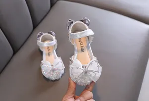 Primo piano di sandali da principessa glitterati argento con dettagli fiocco in strass