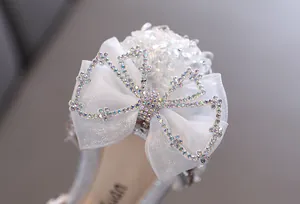 Dettaglio di un fiocco bianco con strass su una scarpa scintillante da bambina