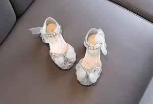 Detailansicht von Mädchen-Prinzessin-Schuhen mit Perlen, Strass und großen Schleifen.
