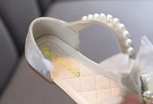Detaillierte Nahaufnahme weißer Mädchen-Prinzessin-Schuhe mit Perlenriemen und Schleifen