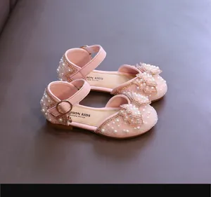 Gros plan de sandales roses pour filles ornées de perles et d'un joli nœud en strass