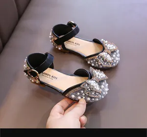 Vue détaillée du nœud en perles et des strass sur les sandales noires pour filles.