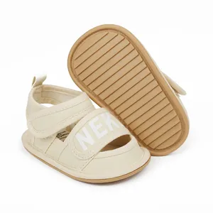 Detailed view of cream baby sandals with NEK text, Velcro strap, and textured sole