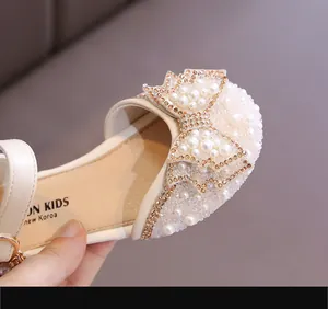 Gros plan sur le nœud élégant en perles et strass des sandales de princesse pour filles