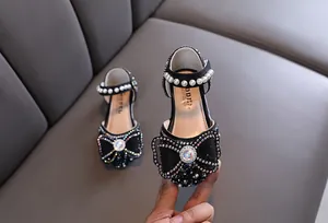 Close-up of girls black princess shoes with rhinestone bow and pearl strap