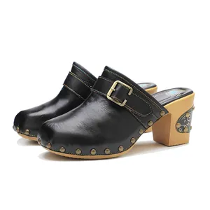 Détail de sabots en cuir noir avec surpiqûres colorées et boucle en métal doré