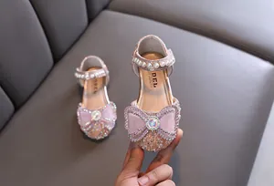 Detailed view of pink glittery girls' princess shoes with bow, rhinestone and pearl accents