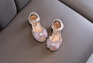 Close-up of pink girls princess shoes with sparkling rhinestones and elegant bows.